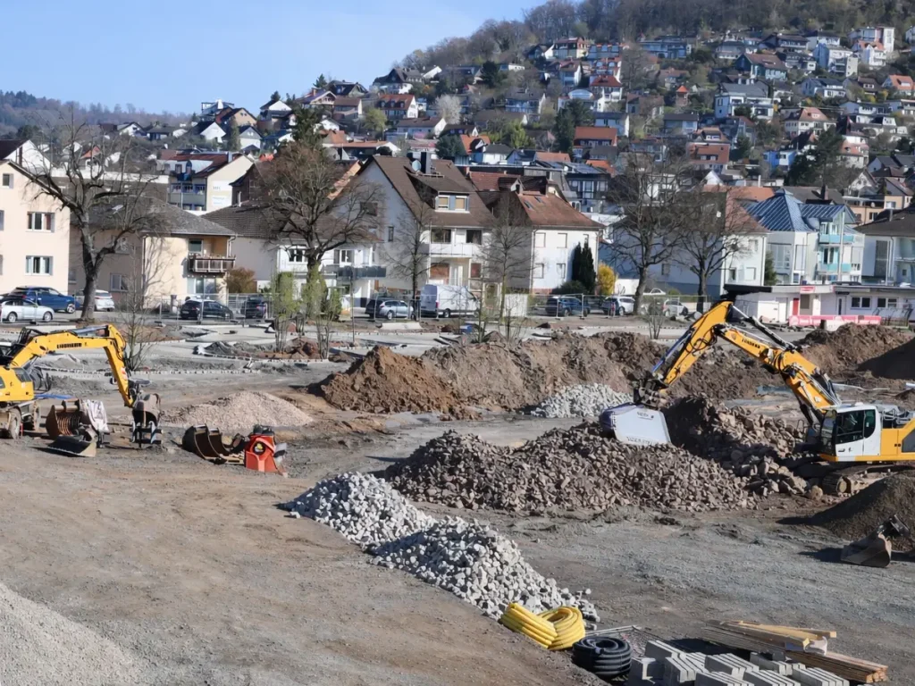 Baustelle im Stadtpark mit Baggern und aufgeschütteten Materialien vor Wohngebiet