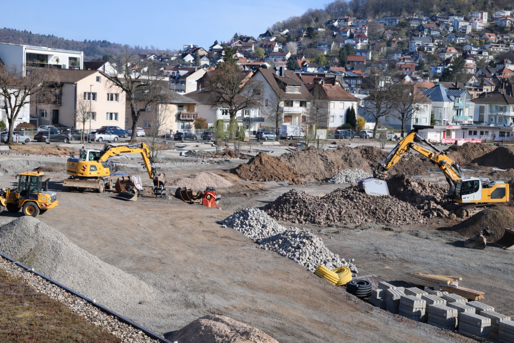 Baustelle im Stadtpark mit Baggern und aufgeschütteten Materialien vor Wohngebiet