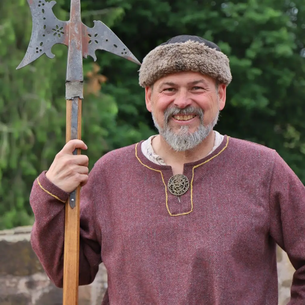 Ein Mann im Gewand eines mittelalterlichen Nachtwächters mit Hellebarde in der Hand.