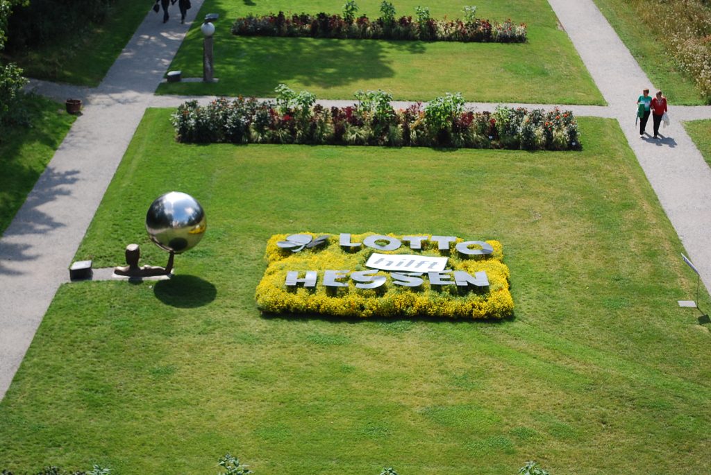 Blumenbeet mit dem Schriftzug „Lotto Hessen“ in einer gepflegten Parkanlage, aufgenommen aus der Vogelperspektive.