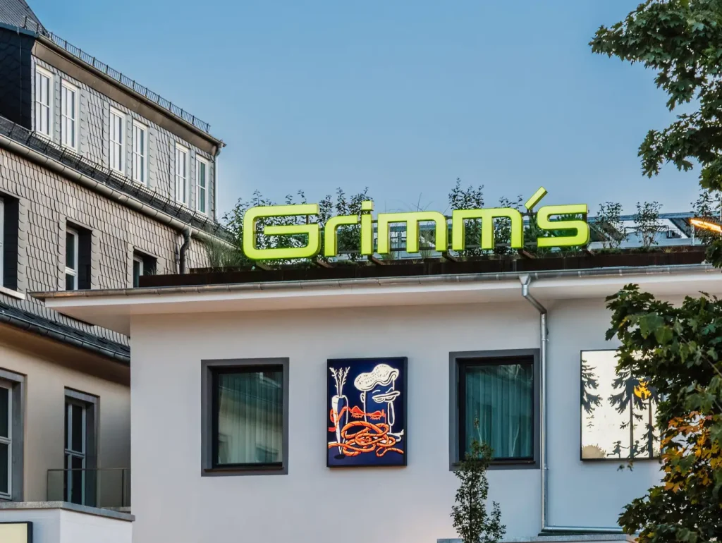 Außenansicht des Grimm’s Hotel Hanau mit modernem Eingangsbereich und markantem Hotel-Schriftzug