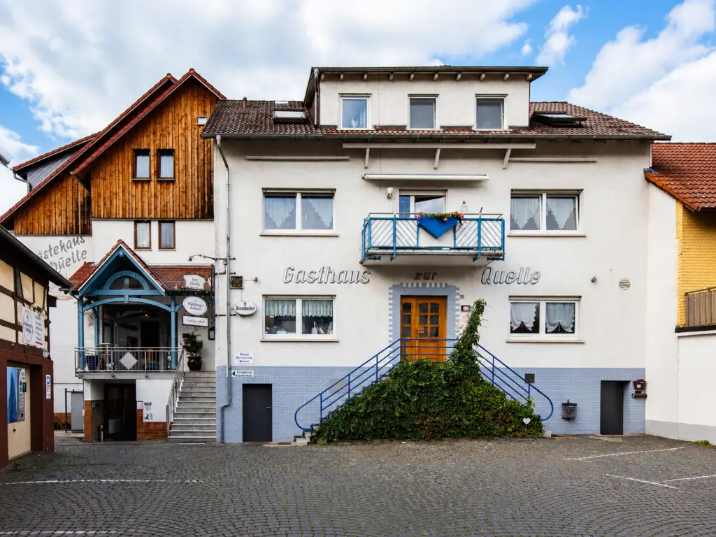 Außenansicht des Landgasthauses Zur Quelle mit Hotelbereich, Eingangsportal und traditioneller Architektur im Ortskern