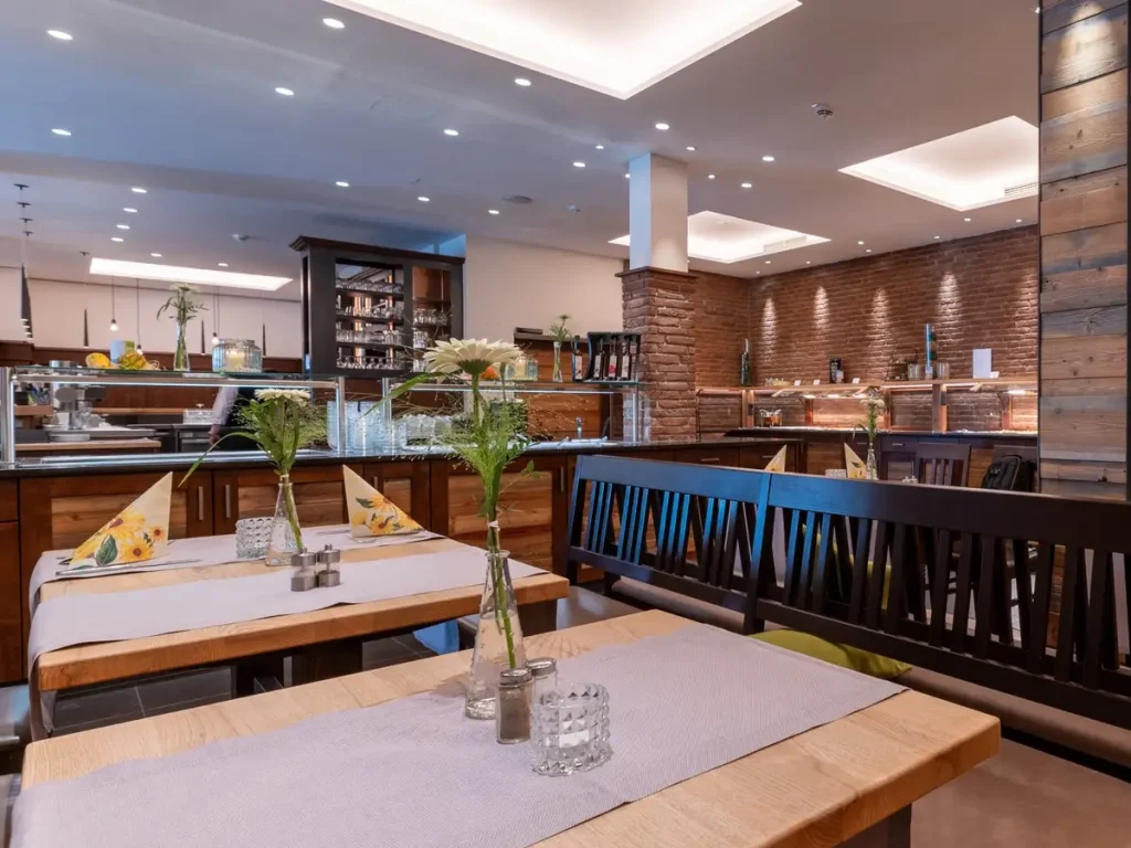 Blick in das Restaurant des ParkHotels Fulda mit stilvoll eingerichteten Sitzbereichen, Holzelementen und moderner Gastronomieeinrichtung