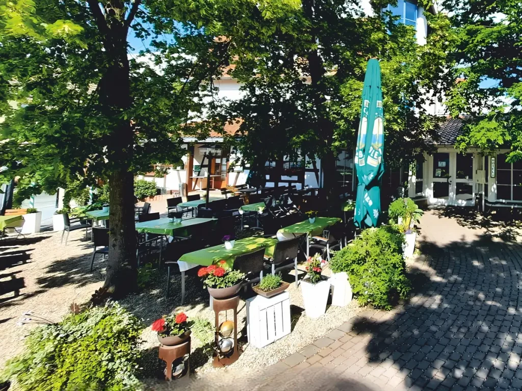 Biergarten des Burghotels Münzenberg mit Sitzplätzen unter alten Bäumen in gemütlicher Atmosphäre.