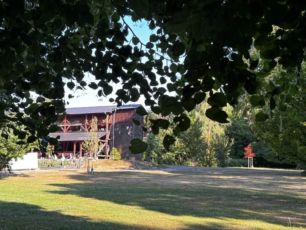 Schattiger Weg unter großen Bäumen mit Blick auf das Gradierwerk im Kurpark Bad Salzhausen