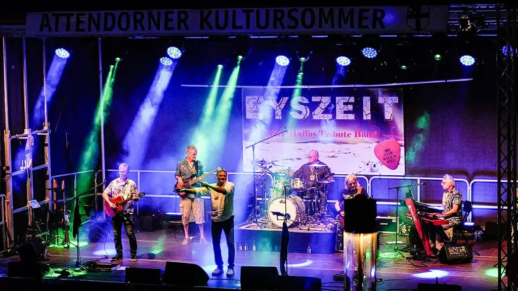 Die Band Eyszeit tritt mit Sänger, Gitarren, Schlagzeug und Keyboard auf einer farbig beleuchteten Bühne auf.