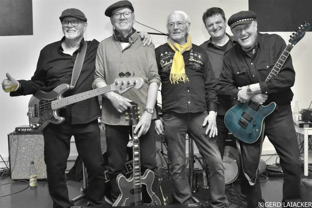 Die fünf Mitglieder der Band The Black Devils posieren mit Gitarren und Bass für ein Gruppenfoto.