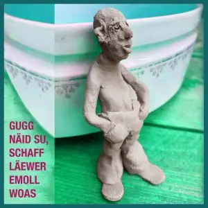 Handgeformte Tonfigur vor einer großen Keramikschale mit grün-türkisem Hintergrund.
