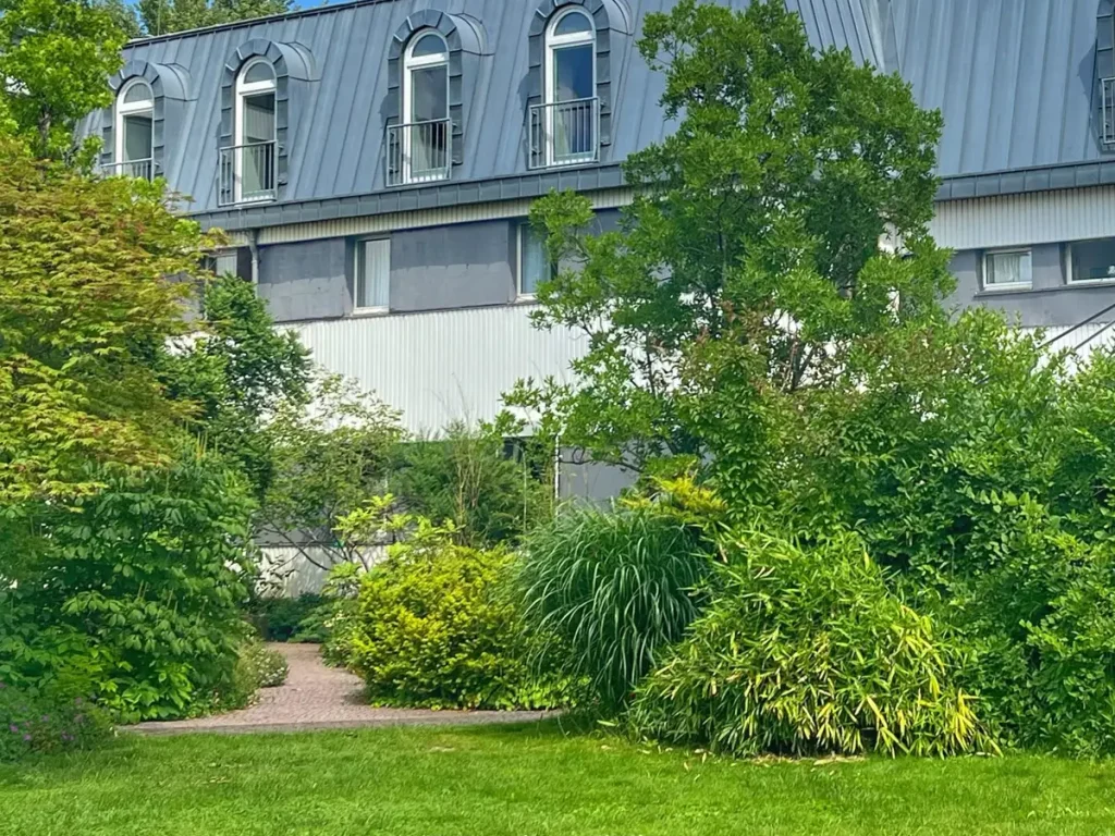 Gartenanlage der Tagungs- und Bildungsstätte mit üppigen Stauden, Gehölzen und einem kleinen Weg.