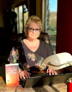 Autorin Silke Jordan sitzt mit ihrem Buch „Sehnsucht am Stummfels“ an einem Laptop.