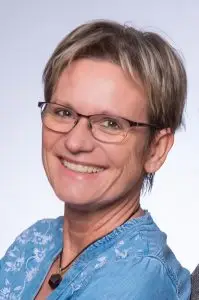 Porträt einer lächelnden Autorin mit kurzer Frisur und Brille.