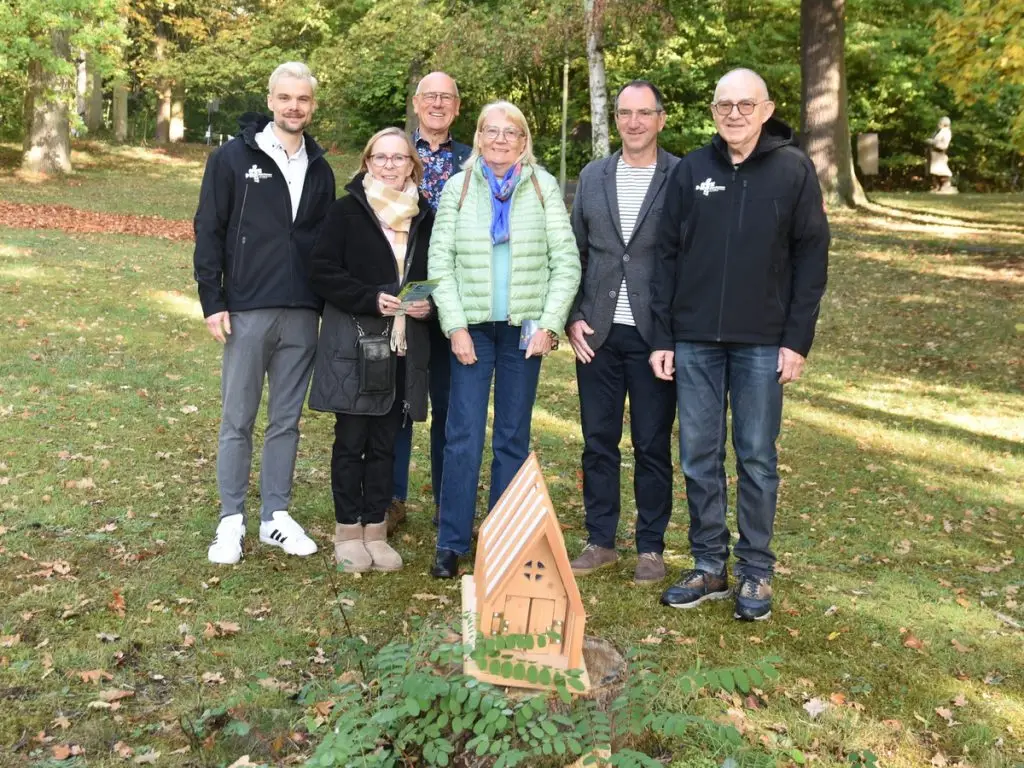 Sechs Personen stehen gemeinsam im Kurpark vor einem Holzmodell der Lichtkirche, die 2027 Teil der Landesgartenschau Oberhessen wird.